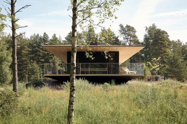 A detached wooden house with a large green yard