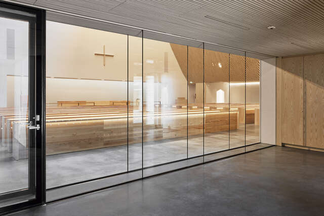 A church altar and pews can be seen through a large glass window
