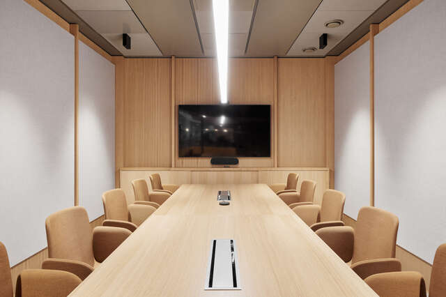 A meeting room with a large table and chairs, with a screen at the end.