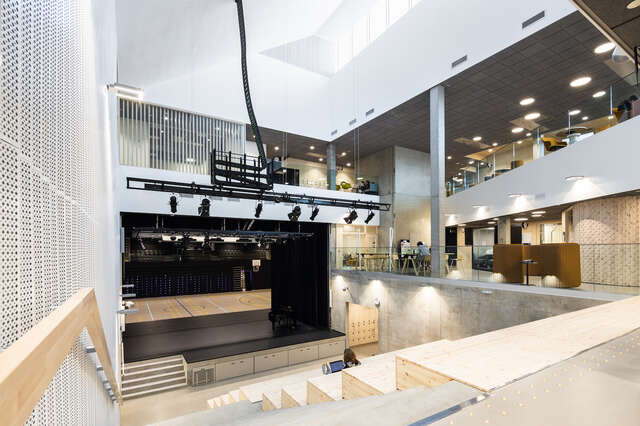 A large, well lit indoor space with a stage and large steps designed for seating