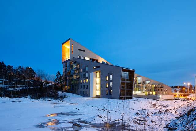 Multiple story residential building with a slanted rood in a snowy landscape.