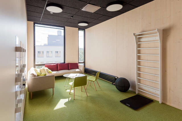 A room with green carpet, chairs and sofas.