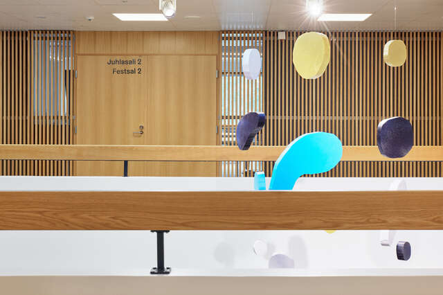 A wooden railing is seen in the foreground, with ornaments hanging from the ceiling in the background