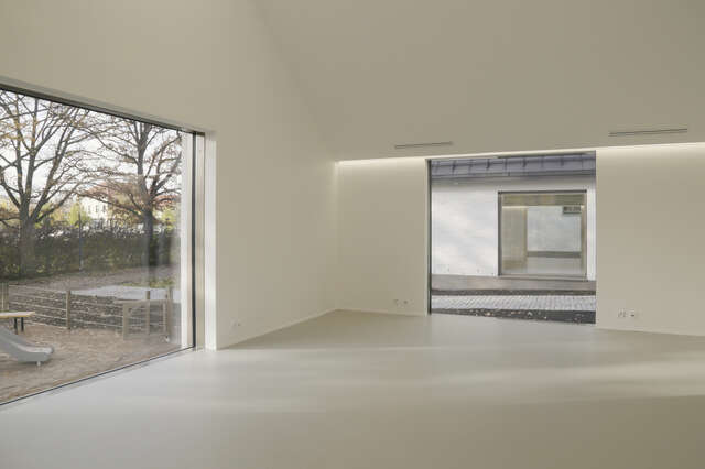 A view of two rooms, with blank white walls. Two windows give in natural light.