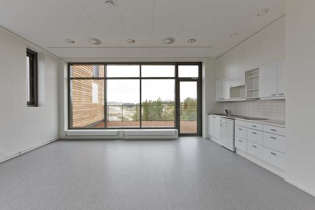 empty kitchen with white walls, grey laminate floors and large windows to the balcony