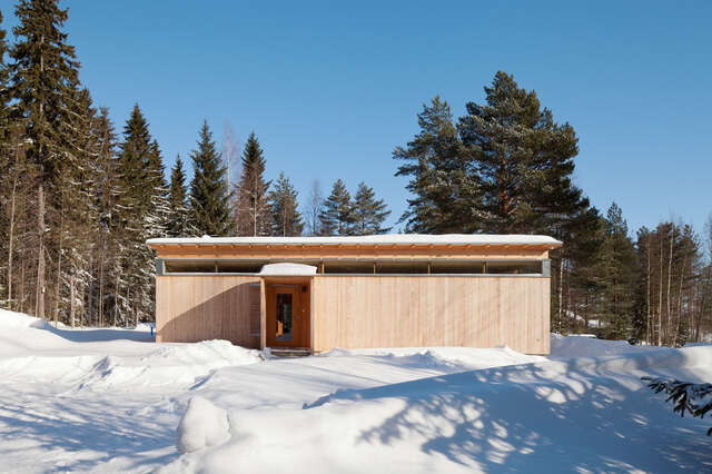 Façade of module-shaped timber building in snowy forest landscape