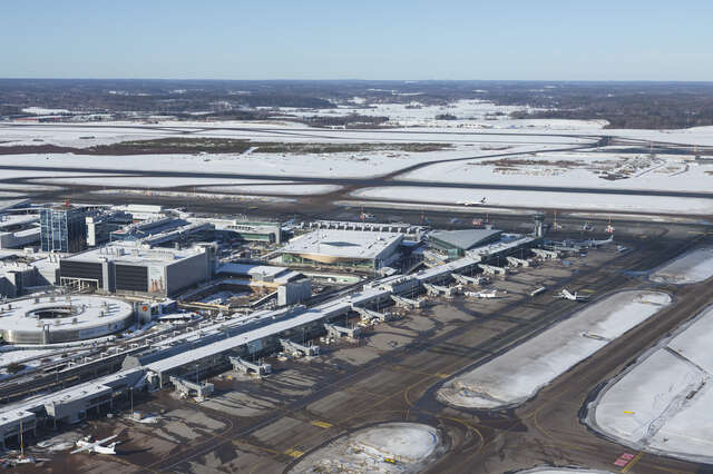 An aerial view of an airport, with scattered buildings and airplanes parked.