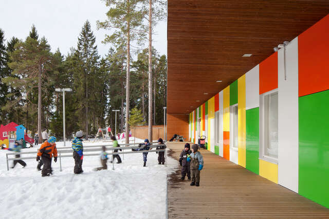 Children playing in the snow and under the canopy beside the colourful façade