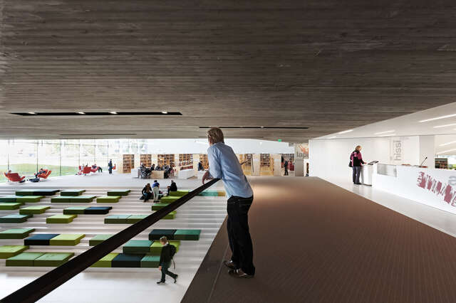 A person leaning on a transparent railing towards a central reading terrace
