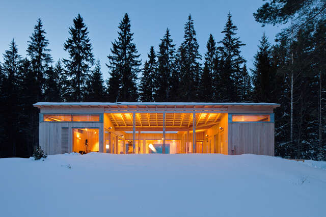 Illuminated central atrium of the timber villa around trees and snow