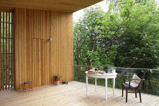 Terrace with wooden floor, walls and ceiling, sitting area and surrounding green trees
