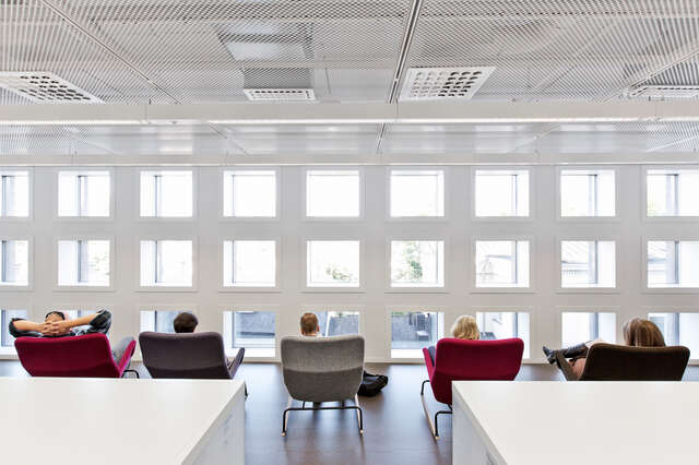 People sitting in armchairs with the view towards a wall of small square windows