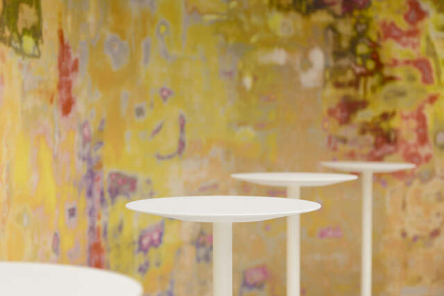 Close-up of standing tables in front of a colourfully painted wall