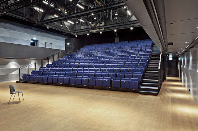 Auditorium with blue seats and wooden floor