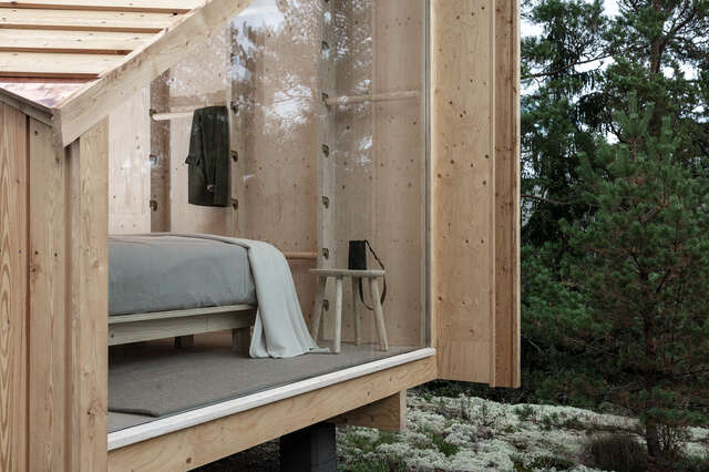 Window of wooden structure showing a bedroom.