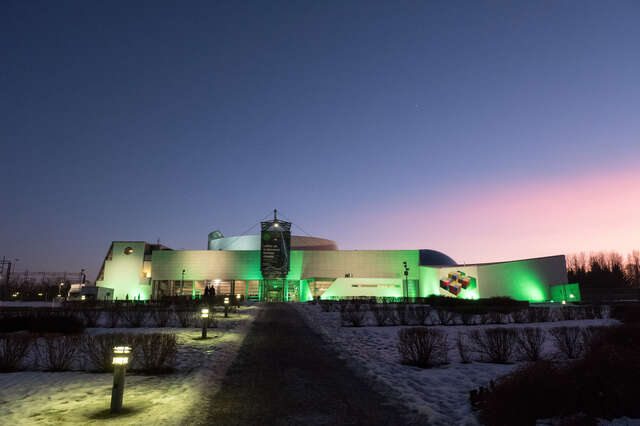 White facade illuminated in green during the sunset.