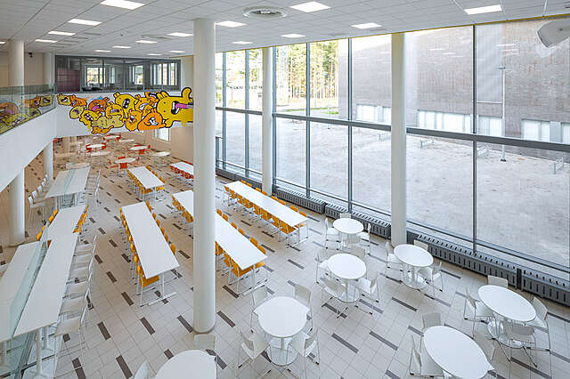 Canteen interior with tables and a glass wall.