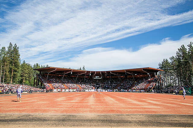 Ground level view from the gravel-covered baseball field towards the stands