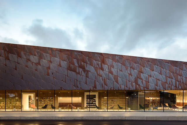 Copper-clad facade with slanted roof, window strip in the lower part with view to reading room