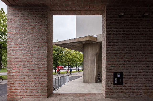Large brick wall with rectangular opening in the middle revealing a walkway.