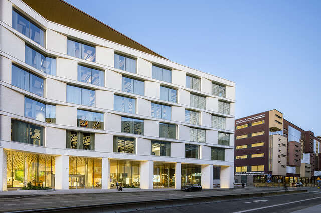 White facade with a wooden top floor, in eveninf light