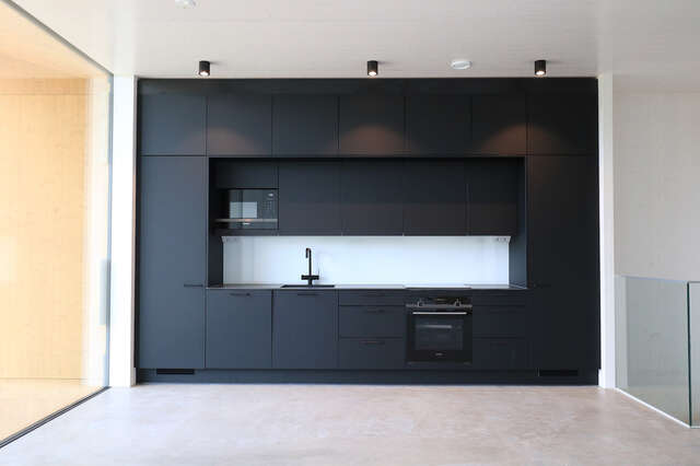 Interior with open kitchen with dark cabinets.