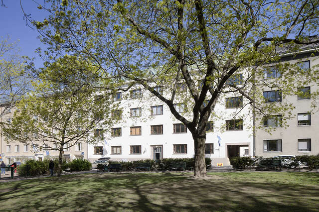 White apartment building with a park in front of it.