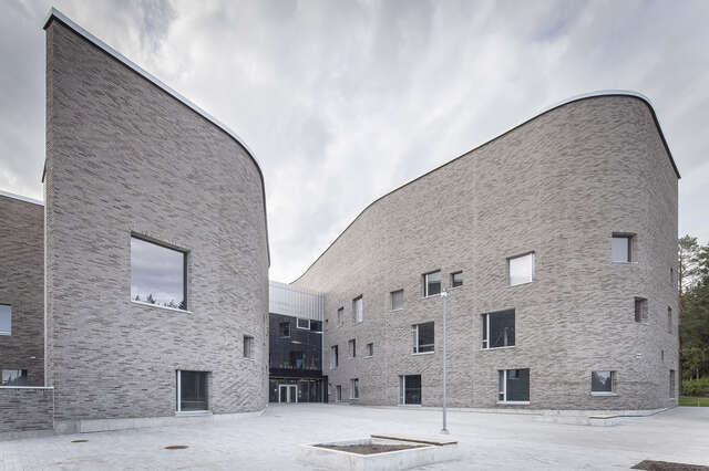 Curved grey-brick facade with square windows in an offset pattern.