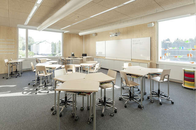 Modern classrooms with wooden surfaces, large windows and moving chairs.