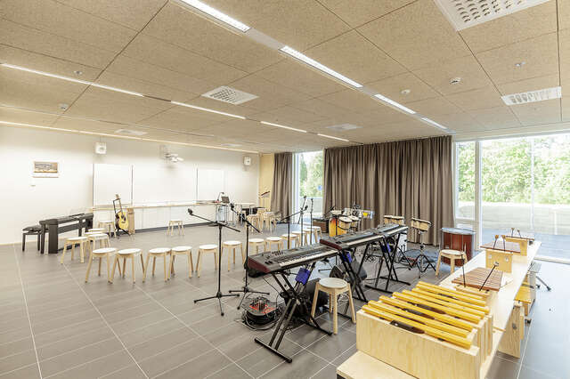 Music room with several instruments, a grey tile floor and stools positioned in a circle.