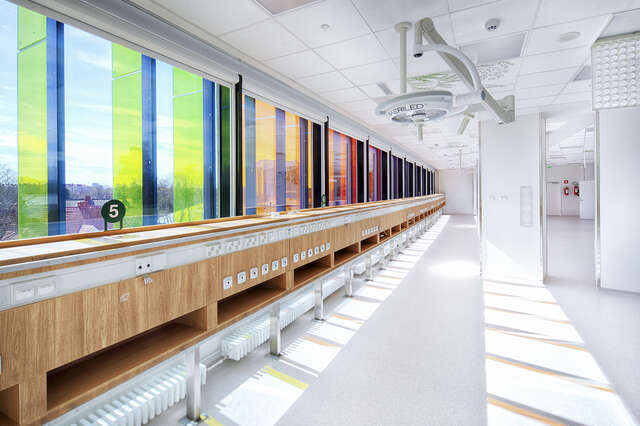 The colorful glass panels on the exterior brighten the white and sterile hospital environment and reflect on the floor.
