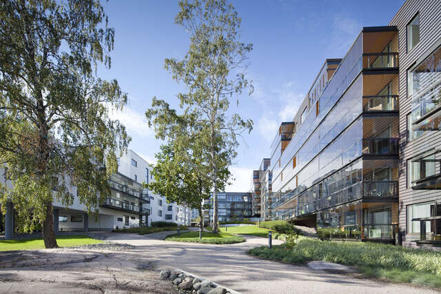 Path surrounded by modern apartment buildings with white, glass and wooden elements.