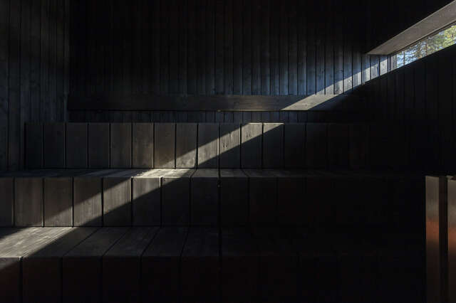 Dark interior of sauna with one sliver of sunlight cutting the image.