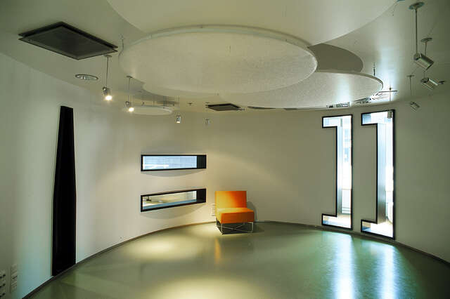 White circular room with an orange armchair.