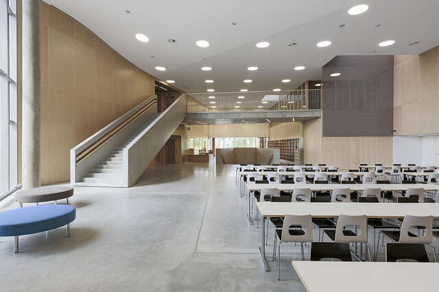 Spacious canteen with neutral colors and mostly wooden furniture.