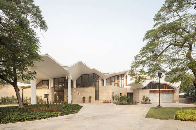 Facade of the embassy building with stone and glass elements as well as a extending white roof.