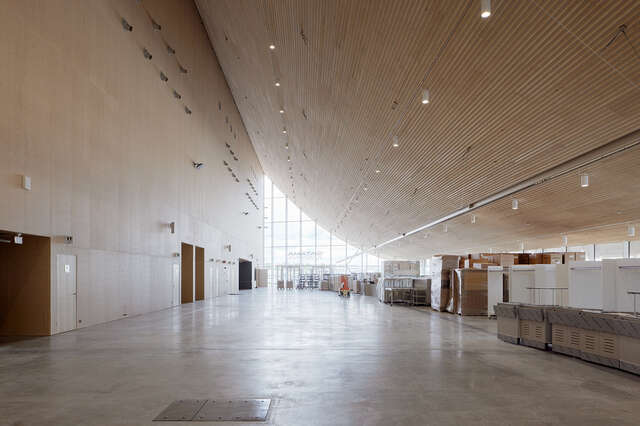 Inside a large space with a hanging, curved wooden ceiling and wall