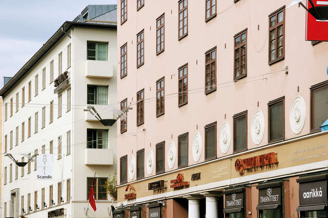Terracotta facade of an old building with brown framed windows and white sculptural medallions.