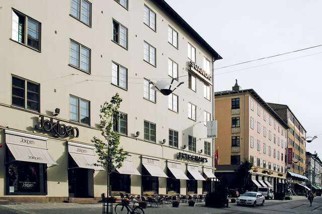 White building with grid windows and shops on the first floor.