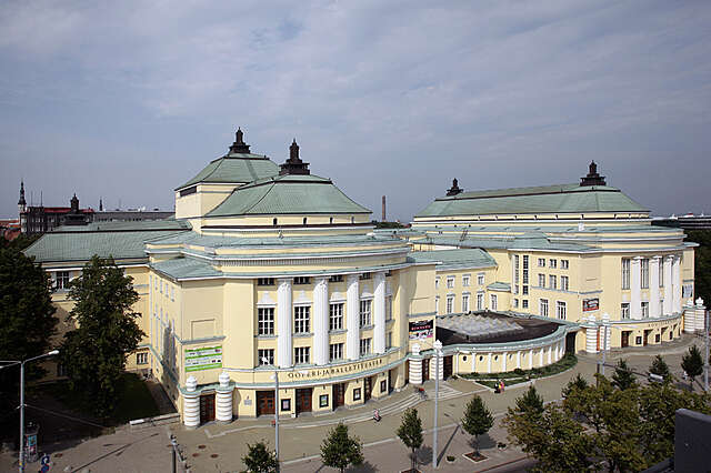 Yellow multiple storey building with white structural elements and decorations from an bird's eye view.