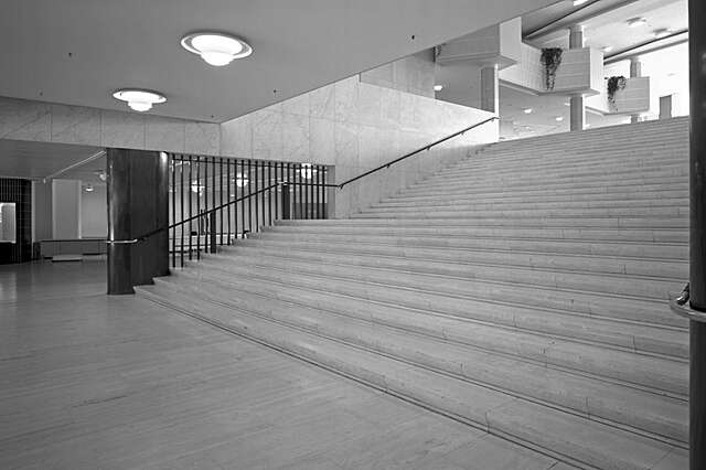 Wide marble staircase with black railings.