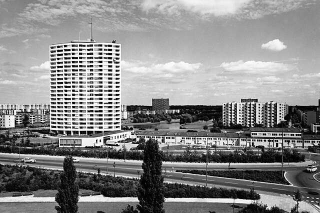 Black and white picture of a white high rise building in the suburbs.