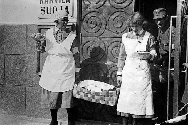 Two women walking with a basket away from the building.