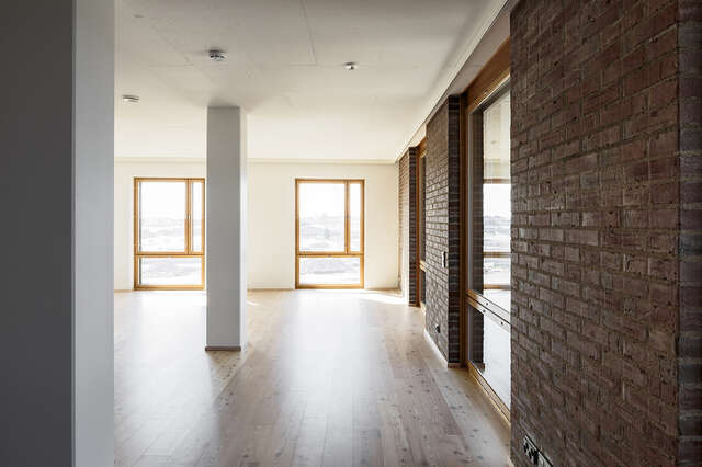 Living room with a bare tile wall on the right and otherwise white walls and ceiling.