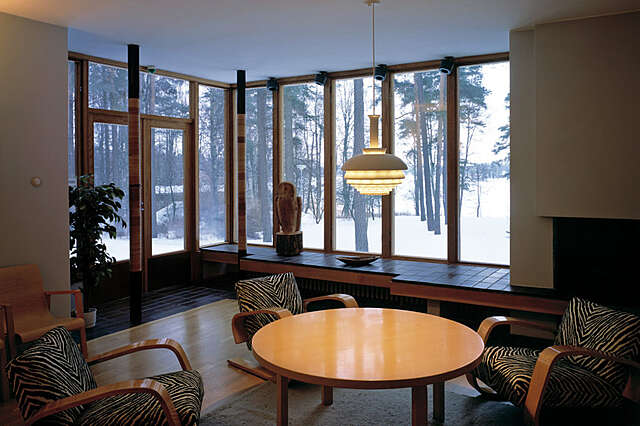 Living room with glass doors to the balcony and a view of the snowy landscape, around the table there are zebra patterned armchairs.