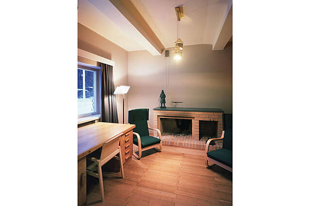 Desk and two armchairs next to a fireplace.