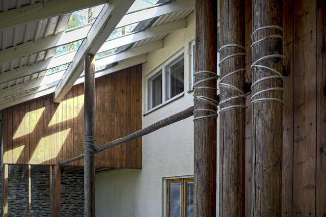 Photo of a veranda with pitched roof and light flowing from skylights installed into the roof. The roof is held up by decorative wooden columns.