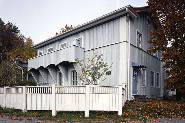 light blue timber house with white details and a fence around the garden.