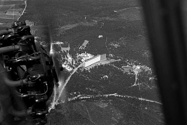 White multiple storey building surrounded by a forest.