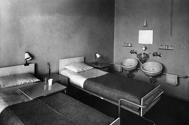 Two beds and sinks in a bare room.